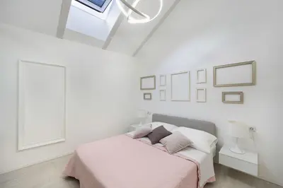 a white bedroom with a bed and a window at Sweethome Gries - Con Garage in Bolzano