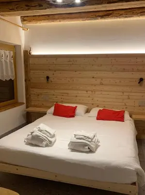 a bed with white sheets and red pillows on it at Locanda al Toal in Moena