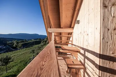 a wooden porch with a bench on the side of a building at Sonus Alpis - Adults Only in Castelrotto