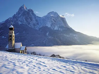 a church on top of a snow covered hill with a mountain at Sonus Alpis - Adults Only in Castelrotto