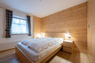 a bed in a room with a wooden wall at Cesa Rosy in Campitello di Fassa