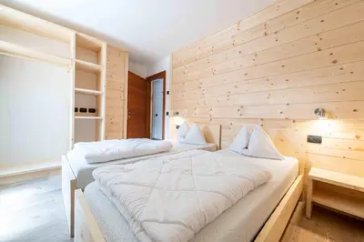 two beds in a room with a wooden wall at Cesa Rosy in Campitello di Fassa