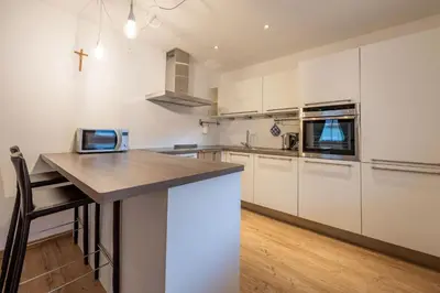 a kitchen with white cabinets and a wooden counter top at Cesa Rosy in Campitello di Fassa