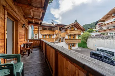 a balcony with a wooden railing with a table and chairs at Cesa Rosy in Campitello di Fassa