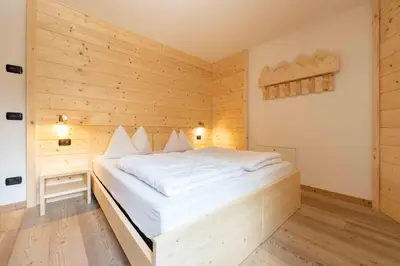 a bedroom with a white bed in a wooden room at Cesa Rosy in Campitello di Fassa