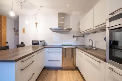 a kitchen with white cabinets and a sink at Cesa Rosy in Campitello di Fassa