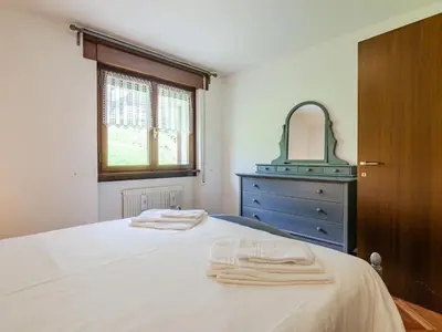 a bedroom with a bed with a dresser and a mirror at Apartment Enrosadira-11 by Interhome in Alba di Canazei