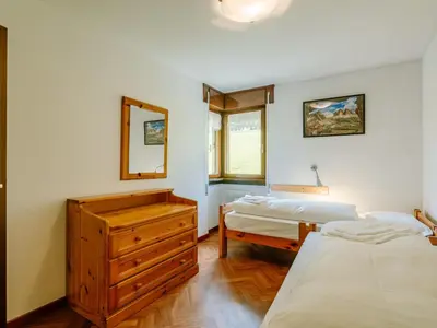 a bedroom with a wooden dresser and a mirror at Apartment Enrosadira-11 by Interhome in Alba di Canazei