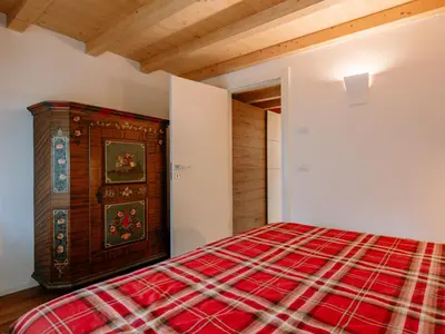 a bedroom with a red blanket on a bed at Apartment Family House by Interhome in Moena
