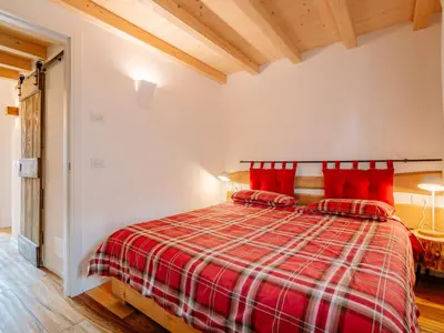 a bedroom with a red bed with red pillows at Apartment Family House by Interhome in Moena