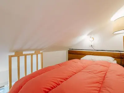 a bed with an orange comforter in a room at Apartment Family House by Interhome in Moena