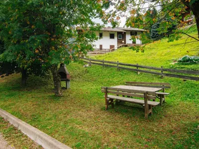 a park bench sitting in the grass next to a house at Apartment Family House by Interhome in Moena