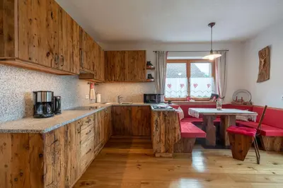 a kitchen with wooden cabinets and a table at Weliserhof in Brunico