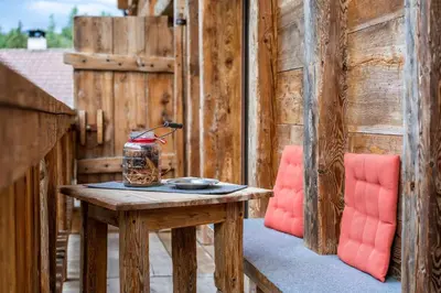 a table on a porch with a red chair at Weliserhof in Brunico