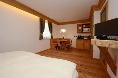 a bedroom with a bed and a dining room with a table at Agritur el mas in Moena