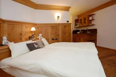 a large white bed in a room with wooden walls at Agritur el mas in Moena