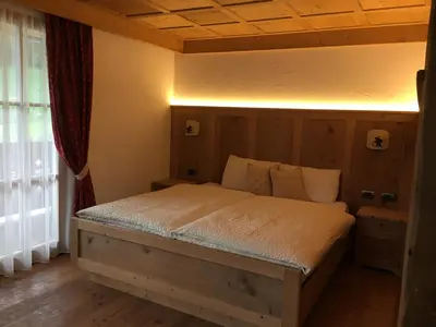 a bedroom with a bed with a wooden headboard at Agritur el mas in Moena
