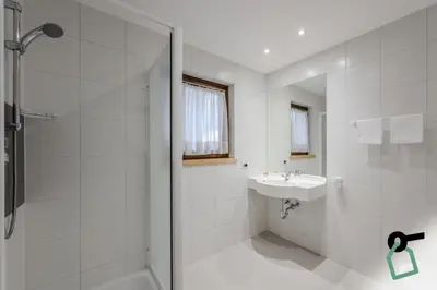 a white bathroom with a shower and a sink at HOTIDAY Apartment Collection - Santa Cristina in Santa Cristina in Val Gardena