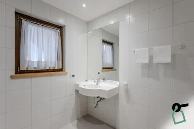 a white bathroom with a sink and a mirror at HOTIDAY Apartment Collection - Santa Cristina in Santa Cristina in Val Gardena