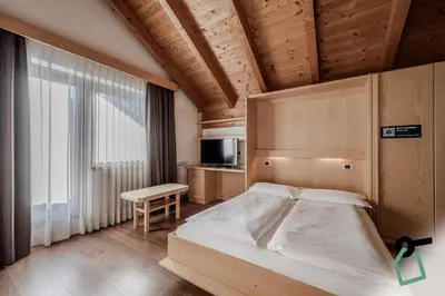a bedroom with a bed and a table and a television at HOTIDAY Apartment Collection - Santa Cristina in Santa Cristina in Val Gardena
