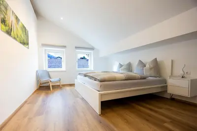 a white bedroom with a bed and a chair at Apartment Weiss-Spitz in Vipiteno