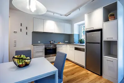 a kitchen with white cabinets and a table with a bowl of fruit at Apartment Weiss-Spitz in Vipiteno