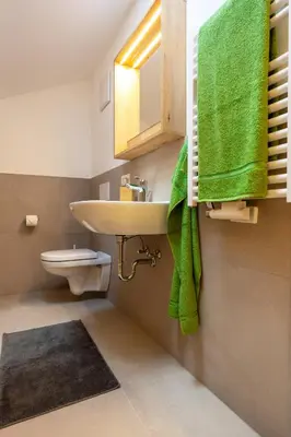 a bathroom with a sink and a toilet and green towels at Apartment Weiss-Spitz in Vipiteno