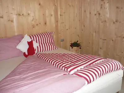 a bed with a red and white striped blanket on it at Apartments Resi in Rasùn di Sotto