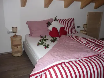 a bedroom with a bed with red and white sheets at Apartments Resi in Rasùn di Sotto