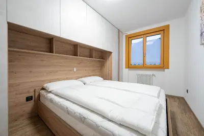 a bedroom with a large white bed with a wooden headboard at Cesa Ricky in Canazei