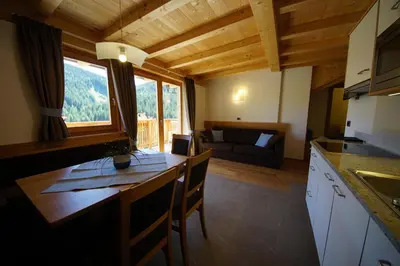 a kitchen and living room with a table and a couch at Costadedoi in San Cassiano