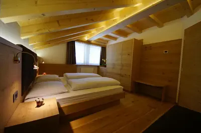 a bedroom with a large bed in a room with wooden floors at Costadedoi in San Cassiano