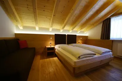 a bedroom with two beds and a couch in it at Costadedoi in San Cassiano