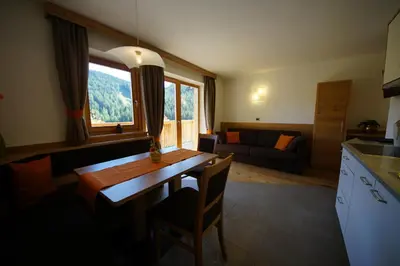 a kitchen and living room with a table and a couch at Costadedoi in San Cassiano