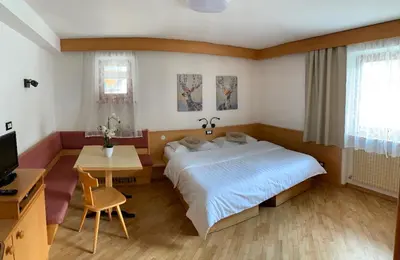 a bedroom with a bed and a table and a television at Bed & Breakfast Garnì Tobià in Campitello di Fassa