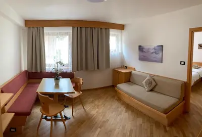 a room with a couch and a table and a bed at Bed & Breakfast Garnì Tobià in Campitello di Fassa