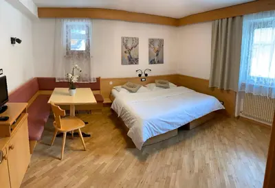 a bedroom with a bed and a table and a desk at Bed & Breakfast Garnì Tobià in Campitello di Fassa
