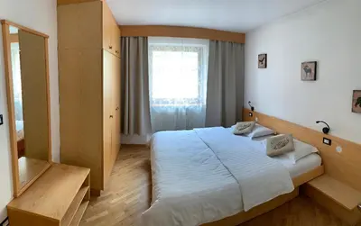 a bedroom with a large bed and a window at Bed & Breakfast Garnì Tobià in Campitello di Fassa