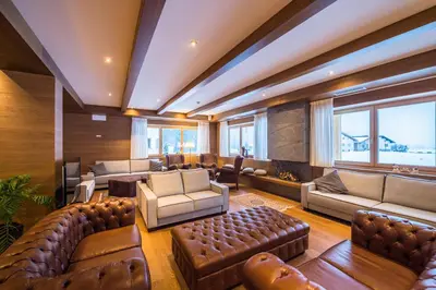 a large living room with leather furniture and windows at Golden Park Resort in Campitello di Fassa
