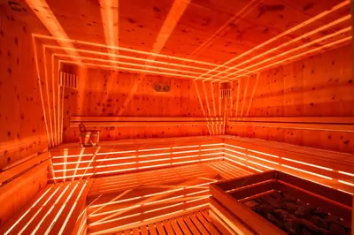 an empty wooden sauna with light shining on the inside at Golden Park Resort in Campitello di Fassa