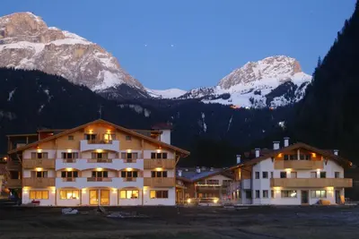 a hotel with snow capped mountains in the background at Golden Park Resort in Campitello di Fassa