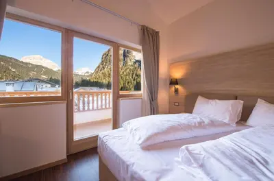 a bedroom with a bed and a large window at Golden Park Resort in Campitello di Fassa