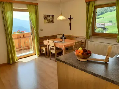 a kitchen and dining room with a table with a bowl of fruit at Ferienbauernhof Masunerhof in Fiè