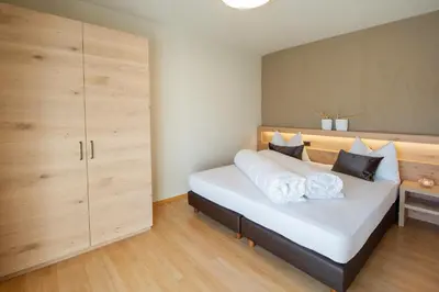 a bedroom with a large white bed and wooden cabinets at Haus Gregori Modern & Central Stay in Vineyard with Rooftop & Served Breakfast in Caldaro