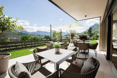a patio with tables and chairs and a view of the mountains at Haus Gregori Modern & Central Stay in Vineyard with Rooftop & Served Breakfast in Caldaro