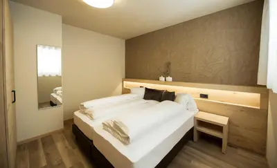 a large white bed in a room with a mirror at Haus Gregori Modern & Central Stay in Vineyard with Rooftop & Served Breakfast in Caldaro