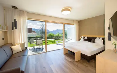 a hotel room with a bed and a couch at Haus Gregori Modern & Central Stay in Vineyard with Rooftop & Served Breakfast in Caldaro