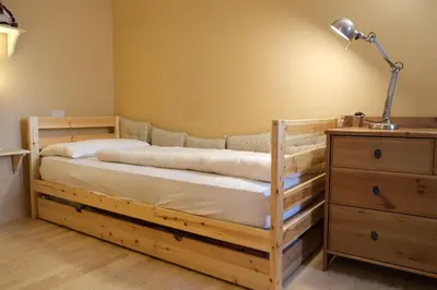 a bedroom with a wooden bed with a lamp and a dresser at Casa Bibi in Campitello di Fassa