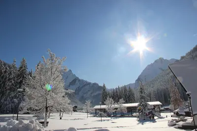 a sun shining in the sky over a snow covered forest at Cèsa Civetta in Canazei