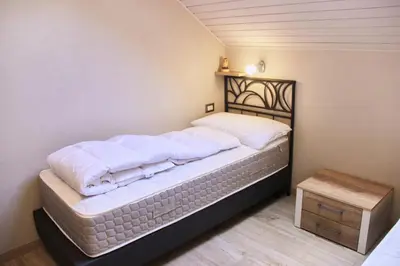 a bedroom with a bed with white sheets and a table at Cèsa Civetta in Canazei